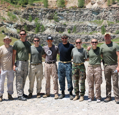 A group of male and female military trainees standing shoulder-to-shoulder in military and tactical gear at the PTF outdoor quarry training range.
